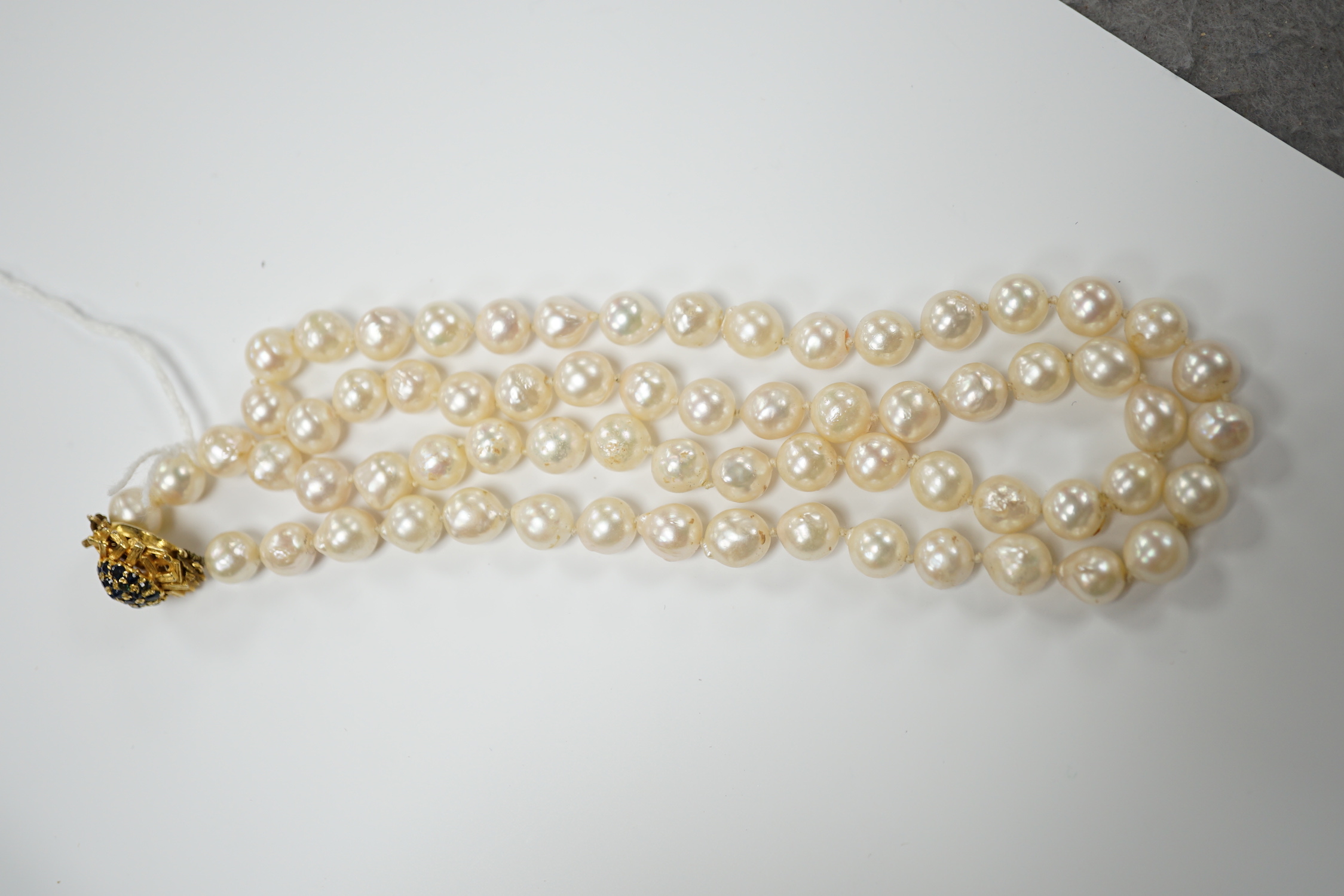 A modern single strand cultured baroque pearl necklace, with 9ct and sapphire set clasp, 66cm.